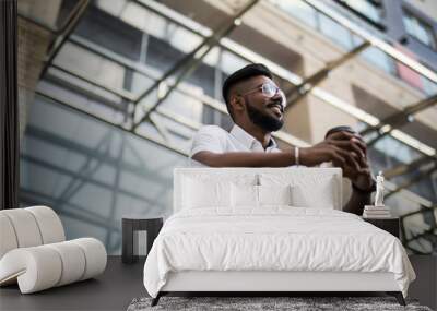 Closeup portrait of a happy young indian man with a drink on his outside balcony, isolated on a city background with roads, Wall mural